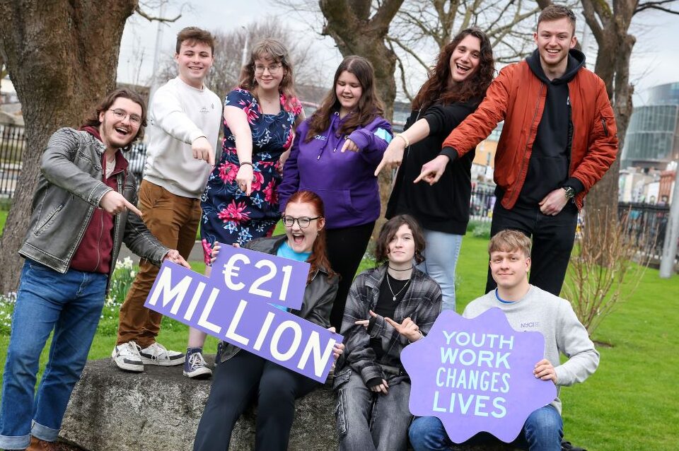 A group of young people holding a sign that says '21 million euro'.
